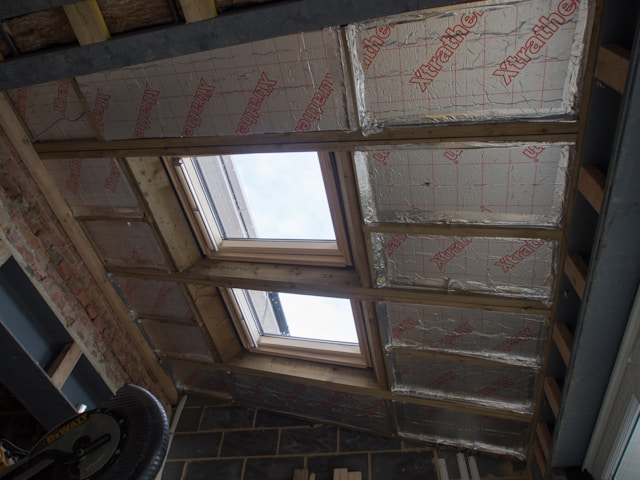 Looking up at insulation being replaced in an attic rooftop with skylight
